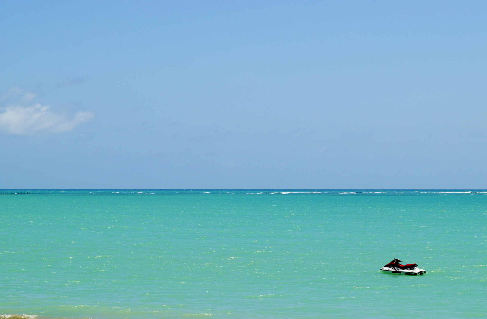 A single personal watercraft sitting on calm open water under a clear sky