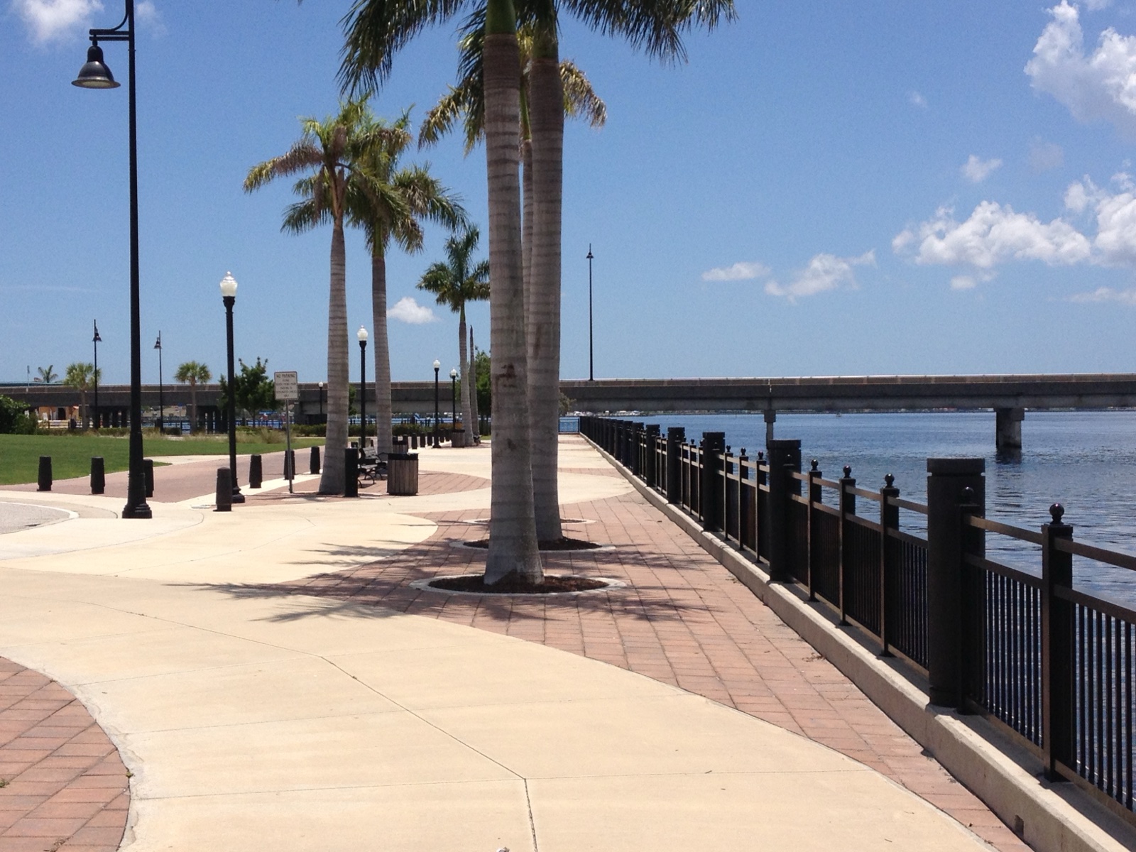 Paved Harborwalk path along the Peace River waterfront in Punta Gorda, Florida, with benches facing the water