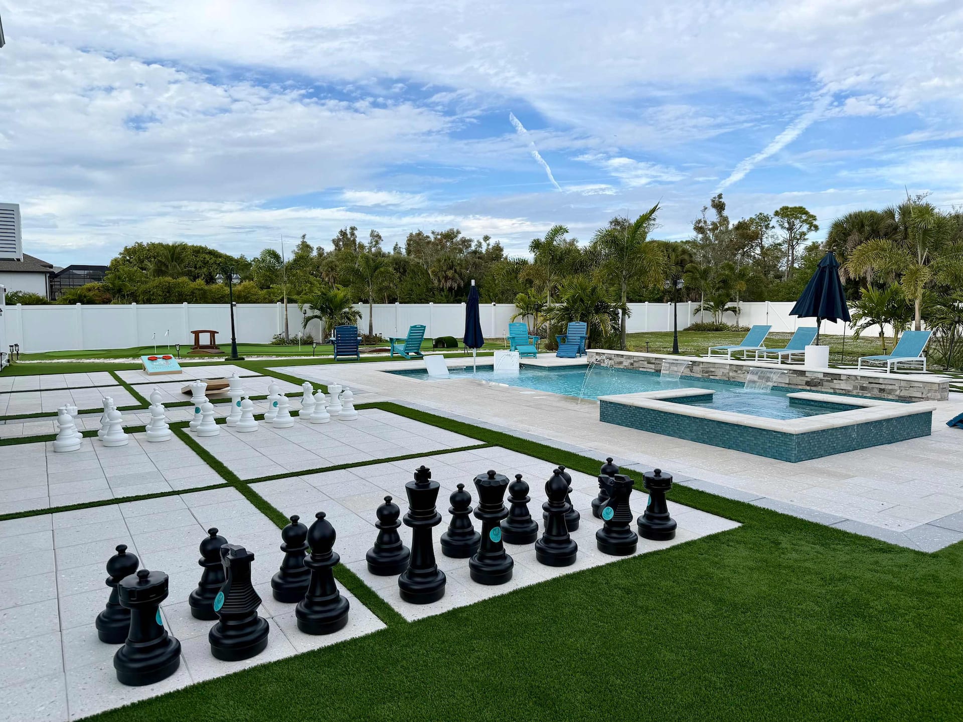 Aerial view of the backyard showing pool, spa, and giant chess lawn game