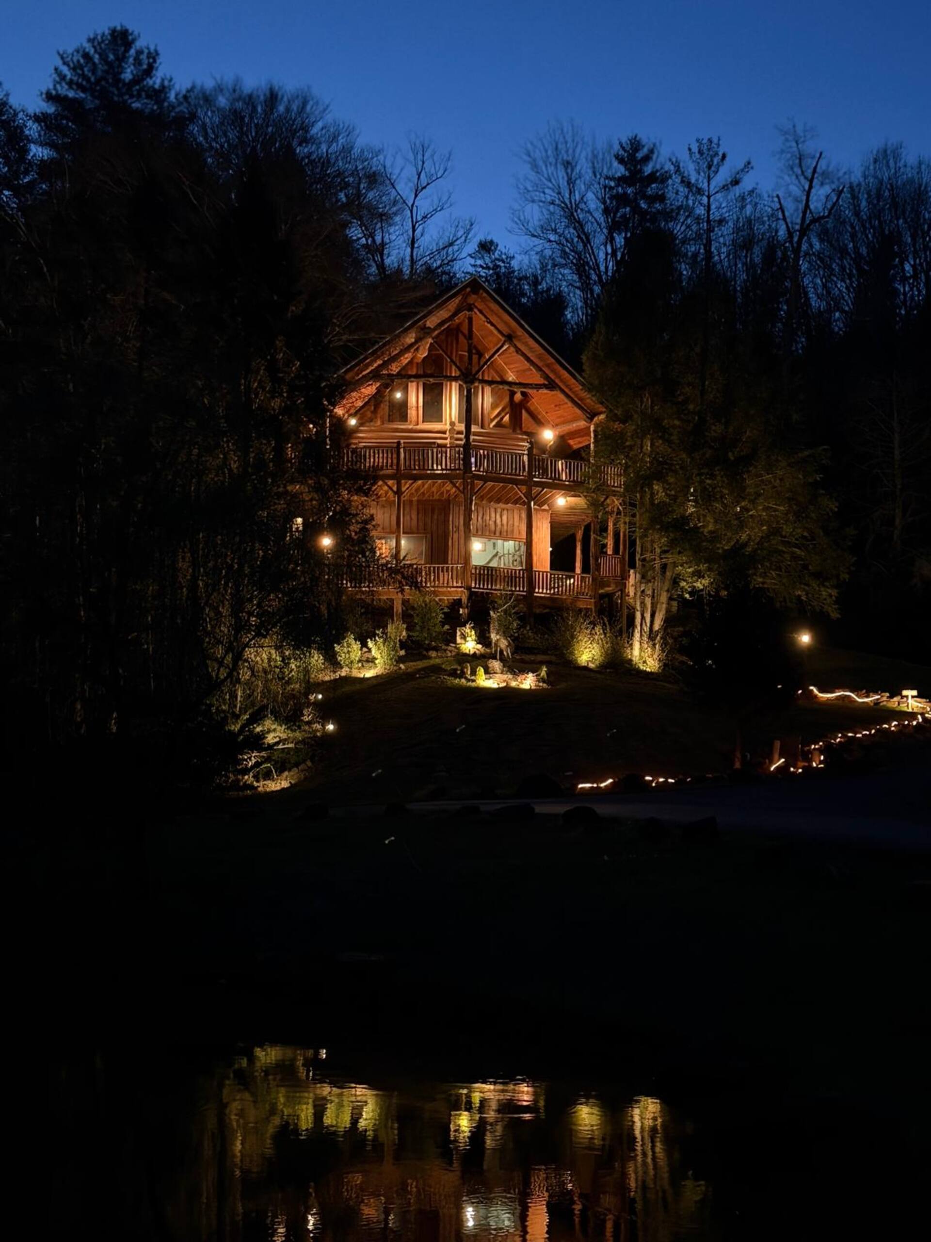 Waters Edge Lodge lit at dusk, reflected in the water below